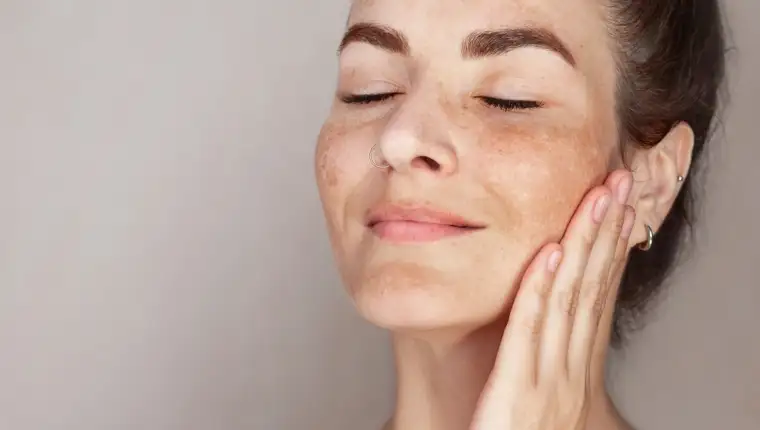 Caucasian woman's face with freckles or age spots, she loves her skin