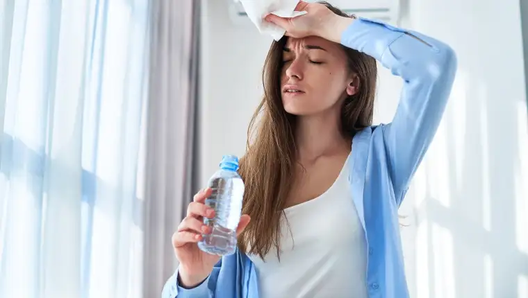 Sweating woman suffering from heat and thirst cools down with ai