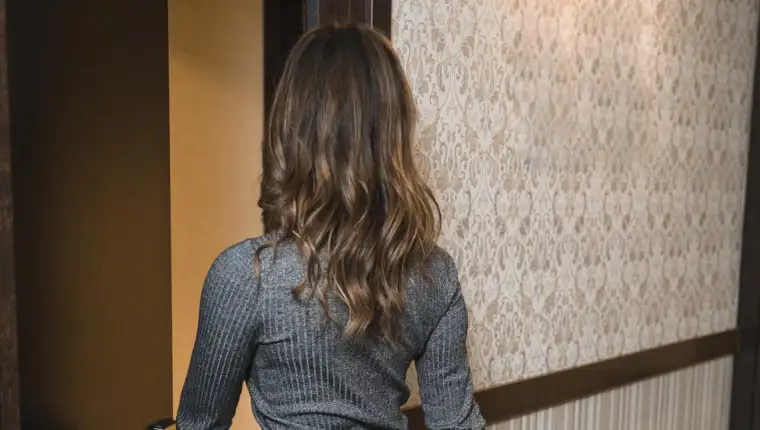 rear-view-blonde-young-woman-with-suitcase-entering-hotel-room