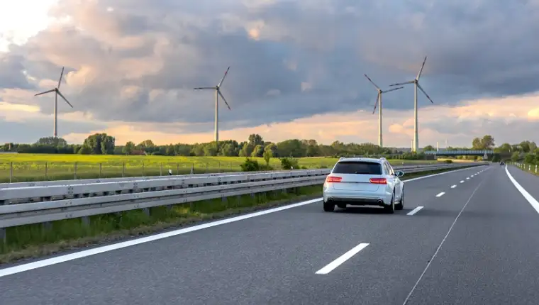 Car on highway. Wind turbines. Renewable energy