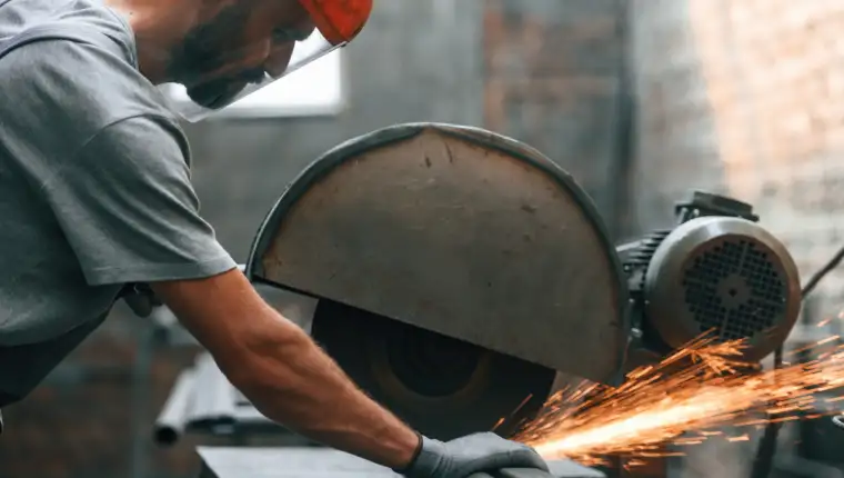 Focused work cutting metal young man factory grey uniform