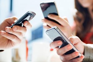 telefon zaražen malwareom troje ljudi u rukama drži mobitele