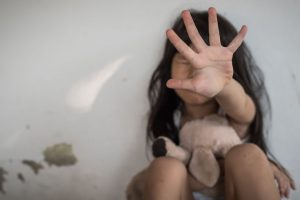 obljubio osmogodišnju djevojčicu pedofil u Prnjavoru ilustrativna slika djevojčica sjedi sa plišanim medvjedićem na krilu ruku u znaku zaustavljanja drži ispred lica lice se n vidi crna duga kosa iza nje sivi zid