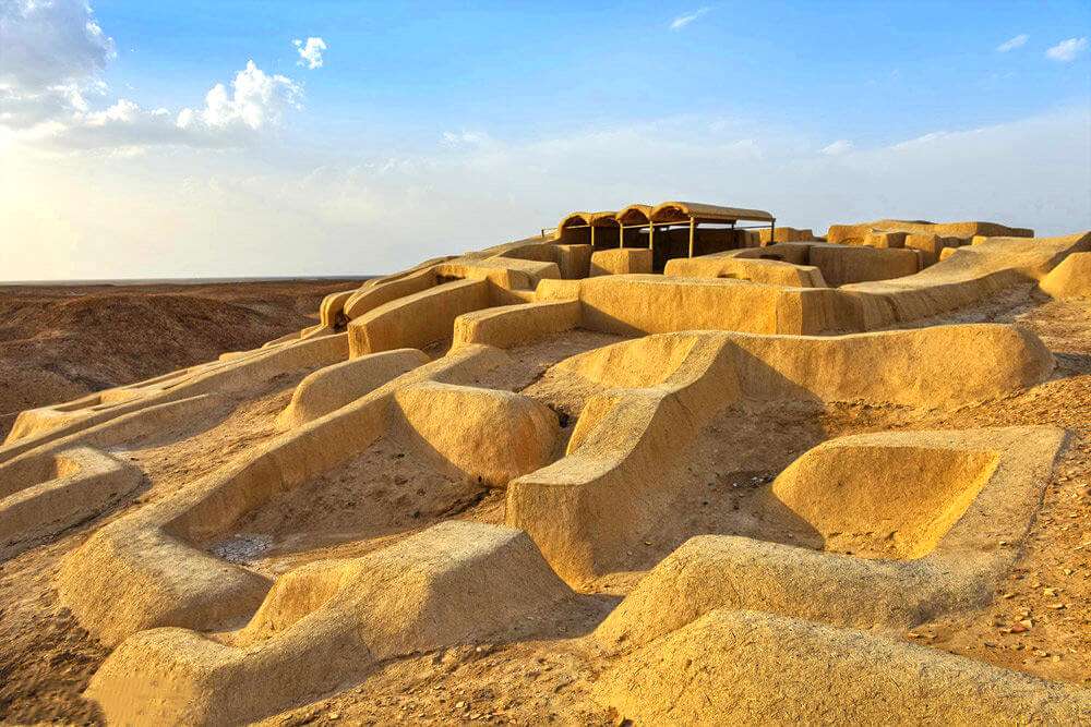 tajne 'spaljene civilizacije' u Iranu arheološko nalazište sa ostacima nasekja od pijeska izgleda kao labirint od pijeska na brdašcu u Iranu na vrhi je mala tenda plavo nebo sa oblacima bijelim