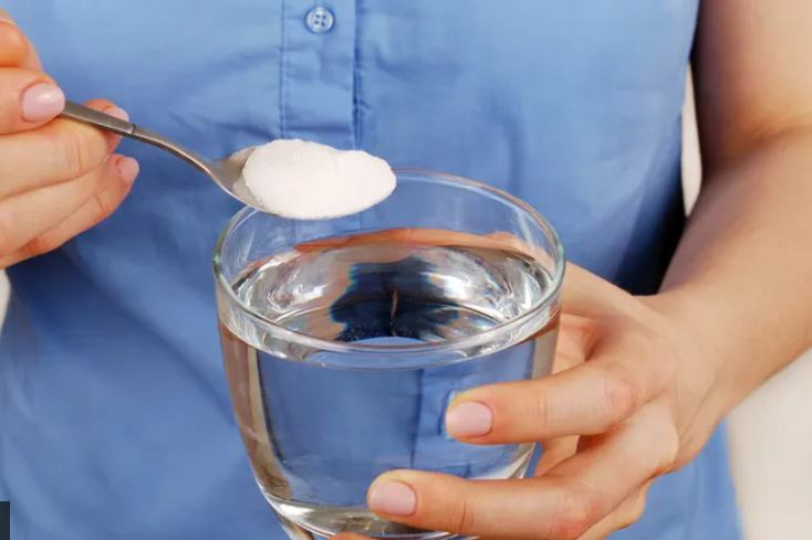 Novi trend žena u plavom stavlja kašiku soli u čašu vode