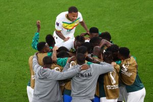 Na utakmici Svjetskog prvenstva Senegal savladao Katar reprezentativci senegala slave grupa sa klup u trenirkama grli se i ljudi pritrčava im igrač u bijelom dresu raduju se trava
