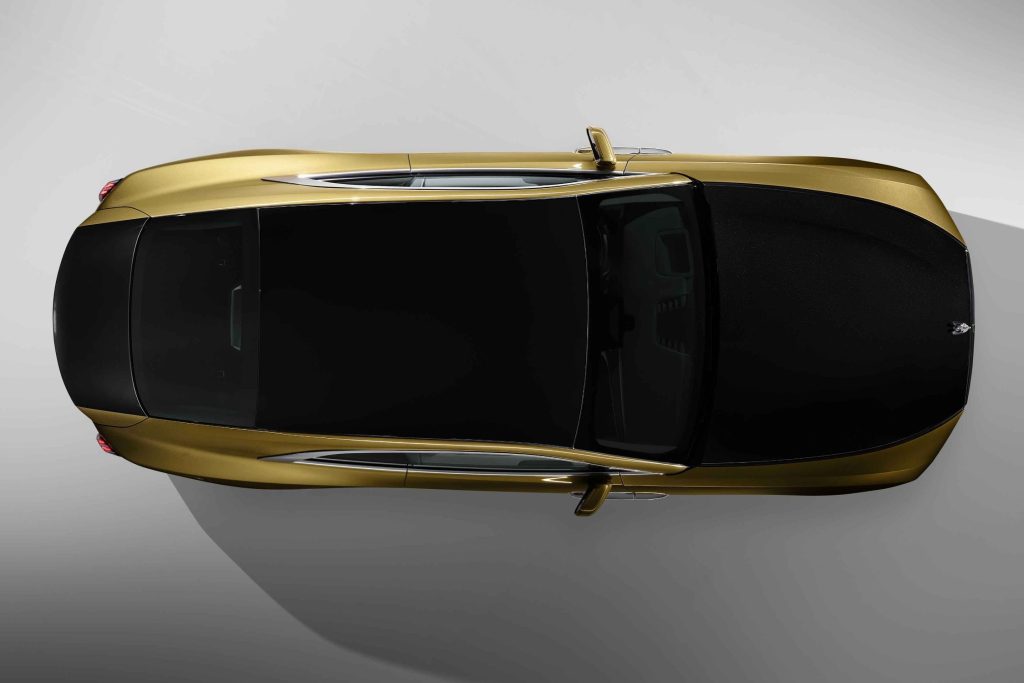 Rolls-Royce novi model Spectre automobil zlatne i crne boje crna boja na dijelu prednje haube i prati liniju preko krova koji je potpuno crn i gepeka siva podloga iza automobila kao da je u prostoriji