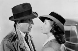 Casablanca scena iz filma lijevo Humphrey Bogart sa šeširpm na glavi u mantilu primaknut IngridBergman kosa uvojci šešir gledaju se kao da su zaljubljeni crnobijela slika