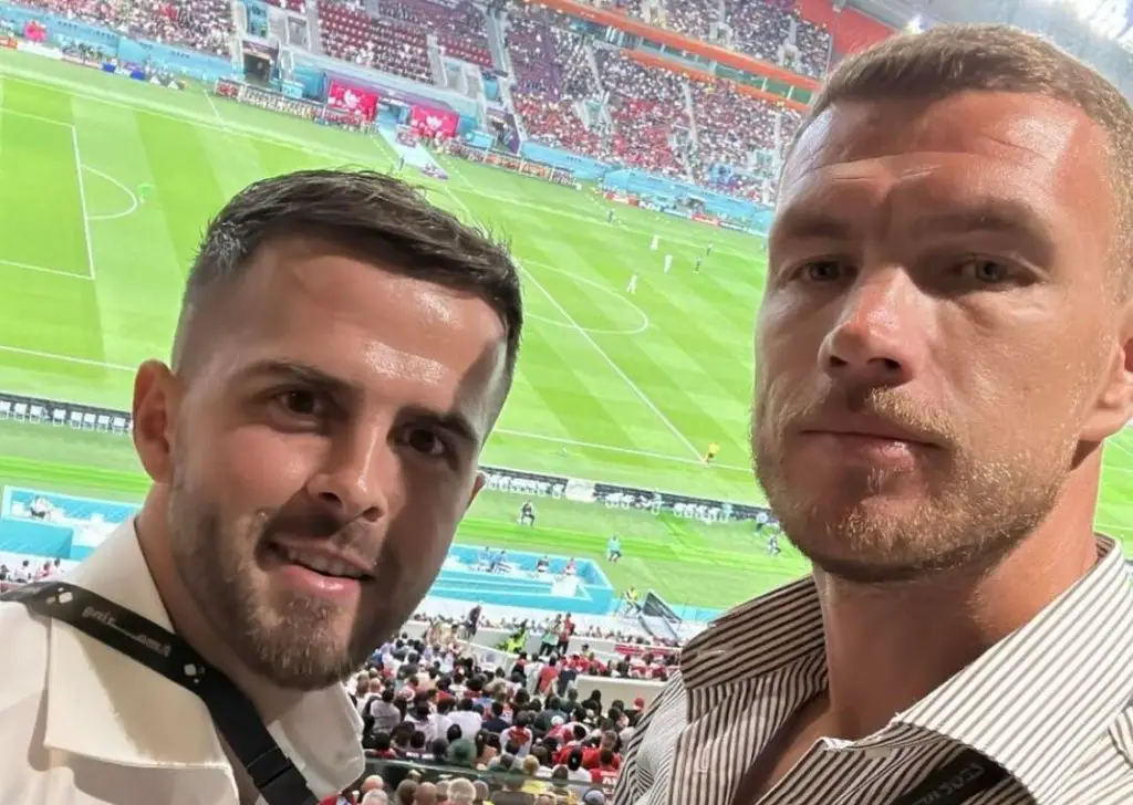 Edin Džeko i Miralem Pjanić gledaju utakmicu iza njih stadion u Dohi igrači na terenu vide im se glave obojica u bijelim majicama pune tribine