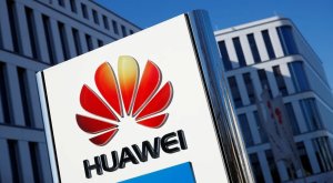 SAD zabranile kineske proizvode sjedište Huaweija zgrada bijela fasaa sa mnogo uskih visokih prozora ispred znak huaweija crveni kao vatra piše ime firme plavo nebo dan