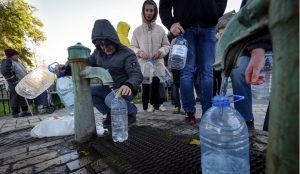Dramatična najava Klička iselit ćemo Kijev građani Kijeva sipaju vodu iz javne česme čovjek u jakni sa kapuljačom na glavi čiči i sipa vodu u prozirnu plastičnu flašu okolo stoje ljudi i djeca čekaju u redu sa flašama vedar hladan dan