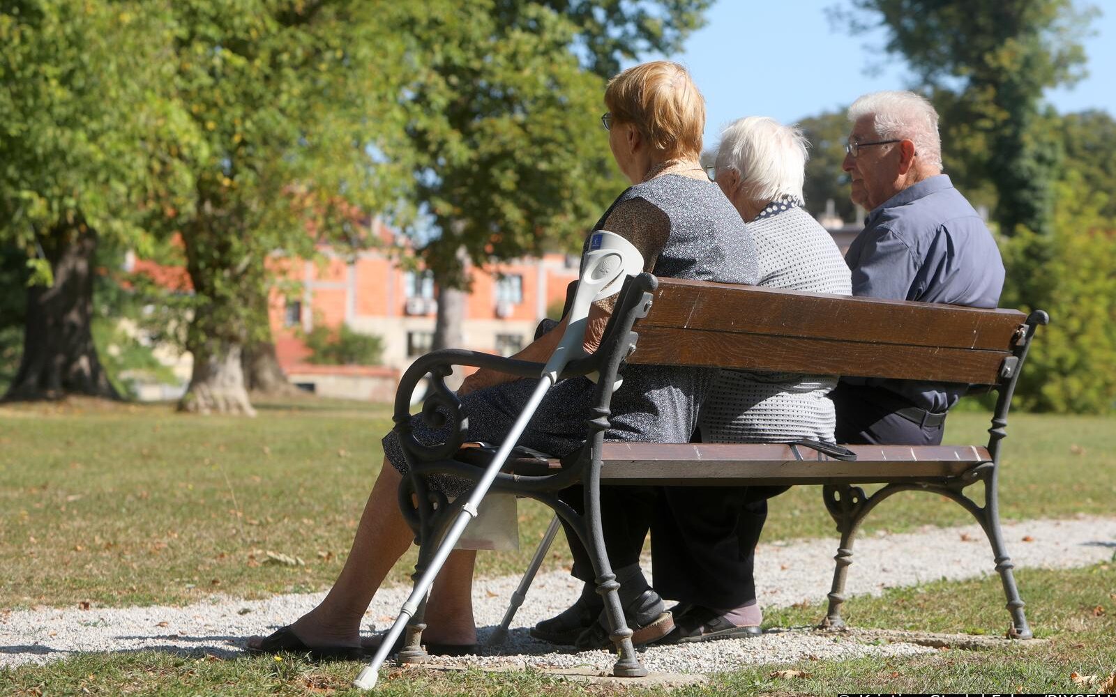 Penzioni sistem troje penzionera sjedi na klupi u parku