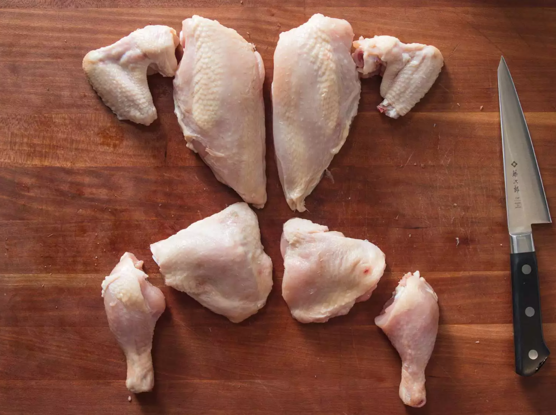 kako izrezati pile kao profesionalac komadi piletine izrezani na drvenoj dasci sa strane nož