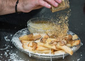 najskuplji pomfrit na svijetu služi se u Njujorku u restoranu Serendipity 3 pomfrit na tanjiru posut sirom i tartufima muška ruka posipa jestive listiće zlata po njemu tamna podloga stola