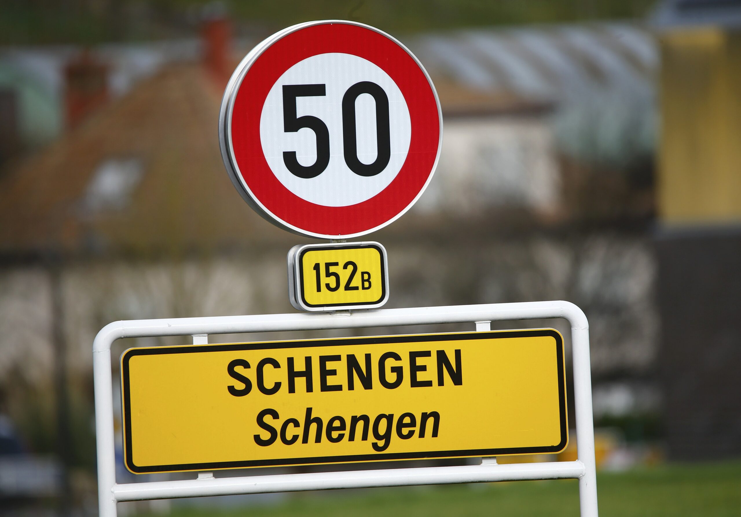Schengen tamla na ulasku u prostor Schengena napisana velikim i malim slovima iznad znak za ograničenje brzine od 50 km/h u daljini kuće dan
