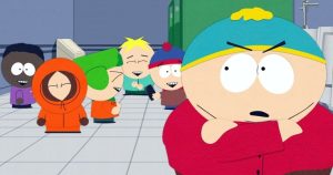 South Park likovi iz South parka njih pet u prvom planu jedan u crvenoj majici i plavoj kapici sa žutom kiticom gleda kao u strahu sa stisnutim rukama na ustima iza u narandžastom odijelu sa kapuljačom sive pločice tamnosivi zid
