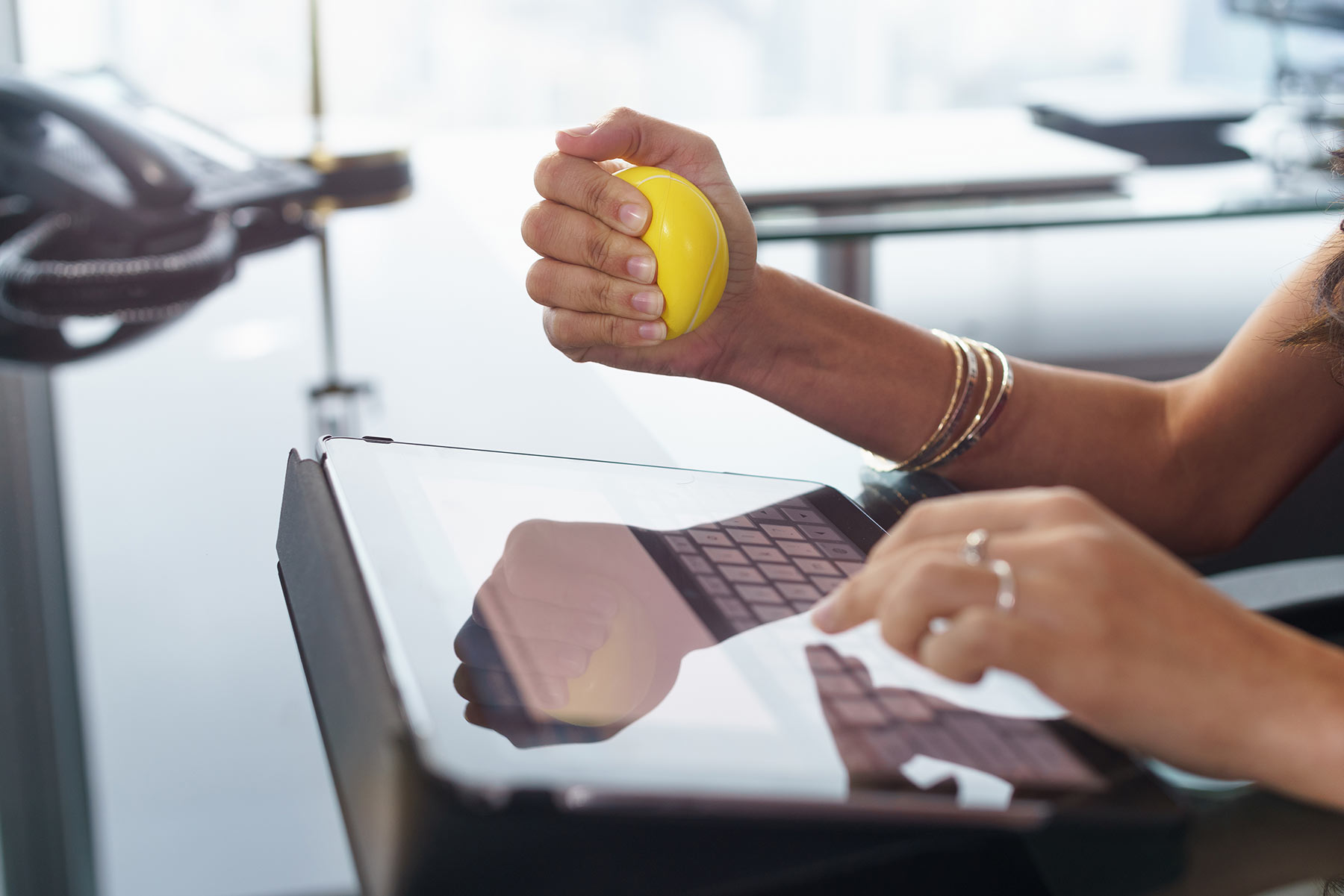 negativnim stresom žena za laptopom drži žutu lopticu u ruci