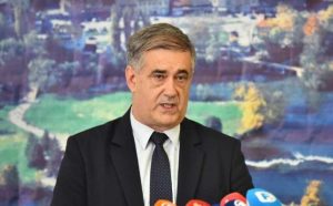 Bihać uskoro bira novog gradonačelnika Šuhret Fazlić daje izjavu crni sako bijela košulja crna kravata ispred mikrofoni iza slika grada Bihaća