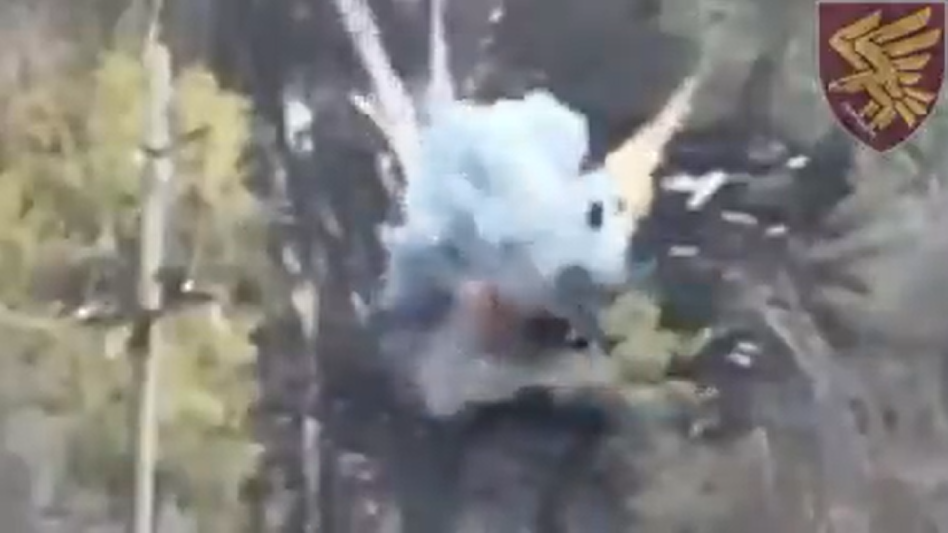 Nevjerovatan snimak drona prikazuje kako ukrajinski vojnik s male udaljenosti uništava ruski tenk fotografija iz zraka vidi se eksplozija tenka okolo šuma i blatnjav put u desnom gornjem uglu grb ukrajinske brigade