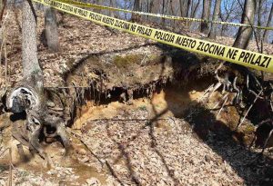 posmrtni ostaci pronađeni kod Srebrenice korijen drveta i blato označeno žutom trakom na kojoj piše ne prilazi mjesto zlločina blato dan