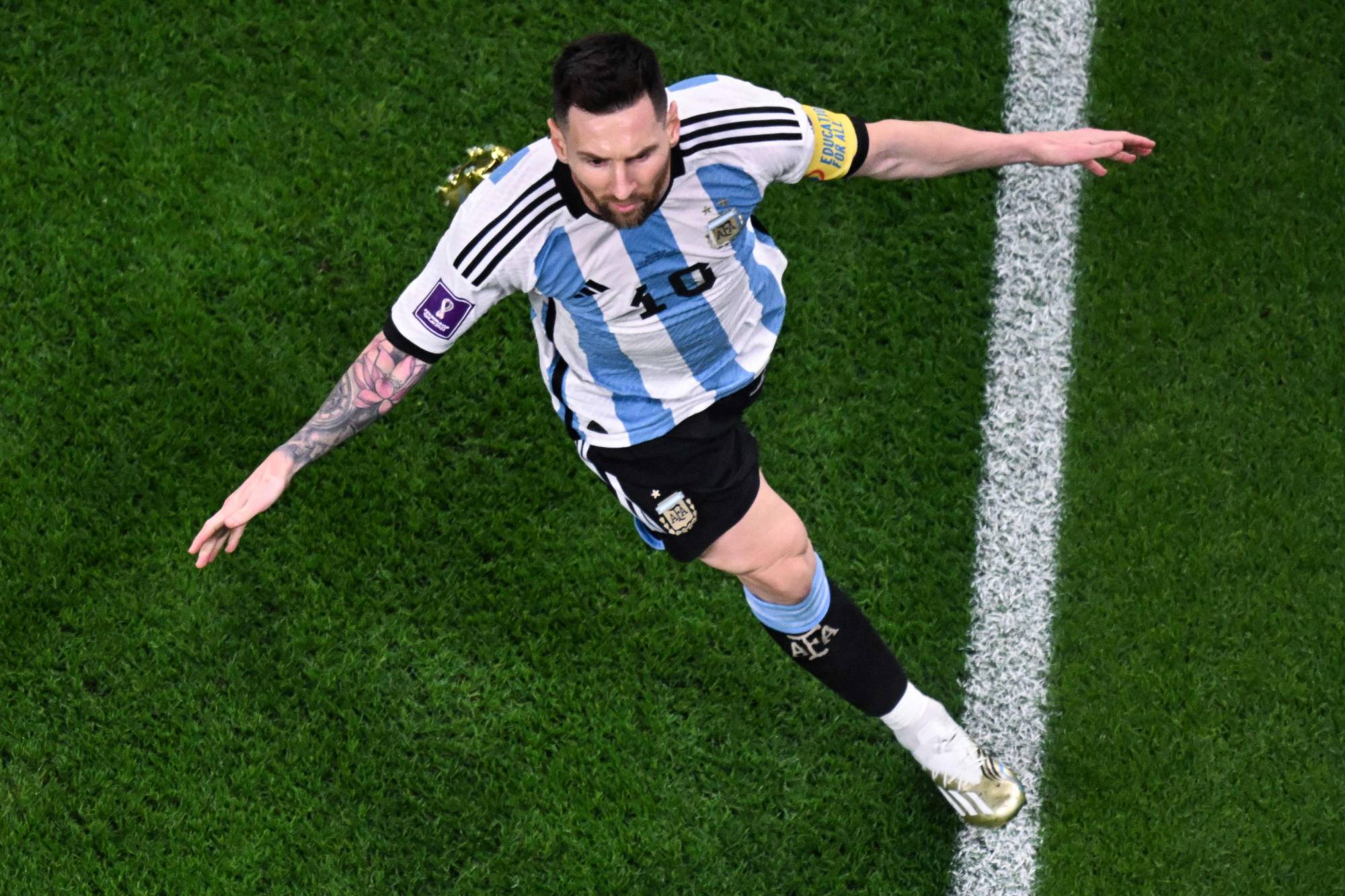 As: Messija sutra čeka njegova posebna žrtva Lionel Messi slikan iz ptičije perspektive u dresu Argentine plavo-bijelom crni šorc bijele kopačke raširene ruke tetovaže po rukama raduje se teren bijela linija ispružena desna noga