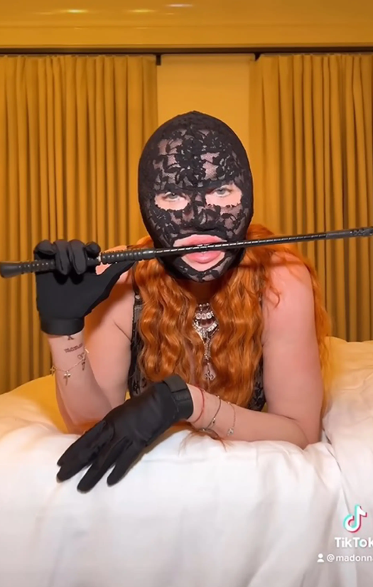 Šta se dešava s Madonnom leži na krevetu potrbuške bijela osteljina crne rukavice čipkasta maska narukvice viri duga narandžasta kosa