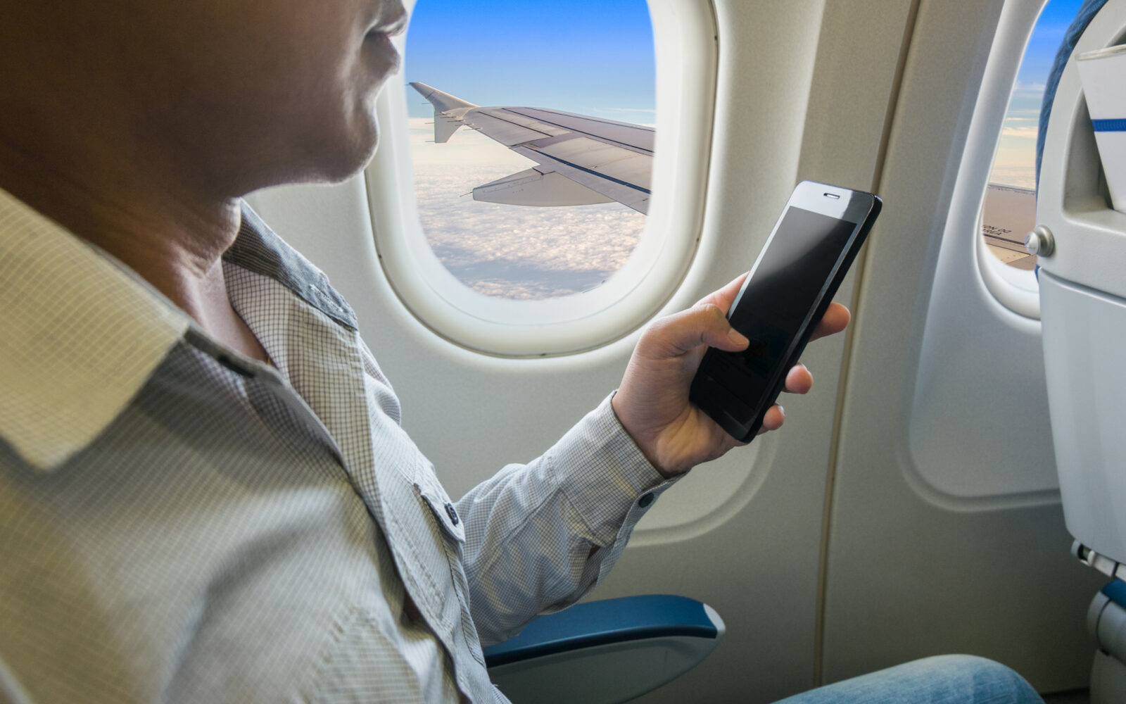 na letovima muškarac drži mobitel u avionu tokom leta