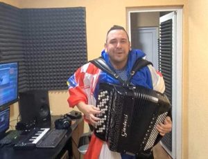 Samir Nurkić svira harmoniku ogrnut zastavom Hrvatske pjeva u studiju