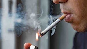 Parlament Novog Zelanda usvojio zakon o ograničavanju kupovine cigareta i duhanskih proizvoda muškarac pali cigaretu upaljačem mnogo dima ne vidi se cijelolice