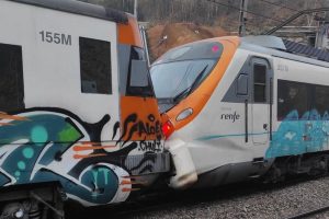 Sudarila se dva voza u Barceloni dva bijela voza prignječene kabine u istoj traci oba imaju narandžaste linije jedan išaran grafitima vidi se pijesak dan