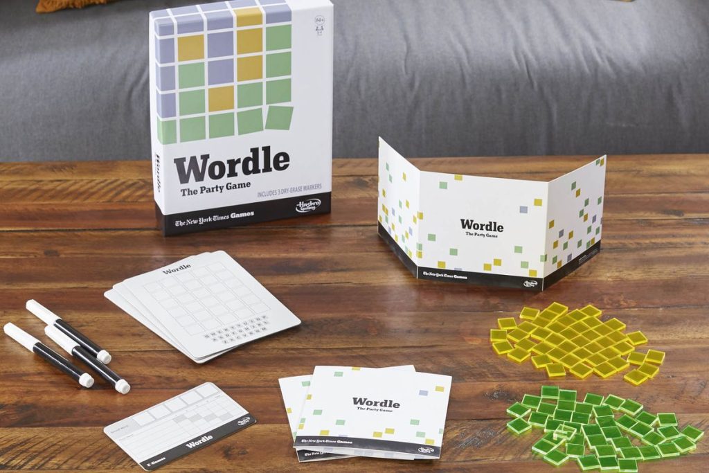 Google tražilica najtraženija riječ Wordle ma drvenom stolu pribor za igranje društvene igre wordle flomaster žuti i zeleni kvadratići kutija na kojoj piše wordle iza sivi kauč