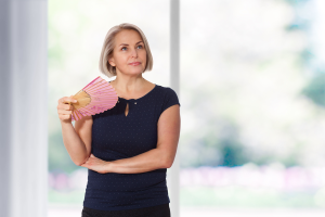 Koji simptomi ukazuju na menopauzu žena stoji i maše lepezom