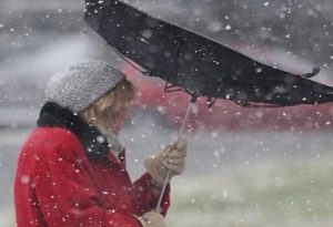 Izdato narandžasto upozorenje olujni vjetar žena drži kišobran kojeg je vjetar izvrnuo crvena jakna bijela kapa snijeg dan